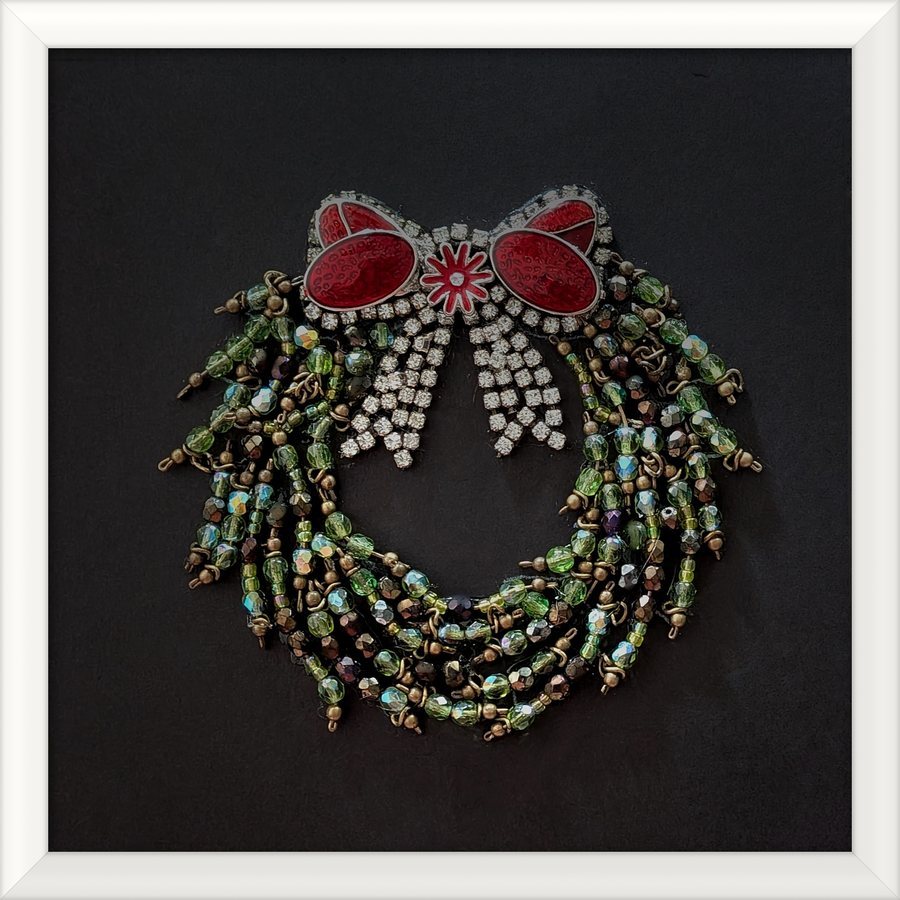 Wreath jewelry art with a red bow in a white frame
